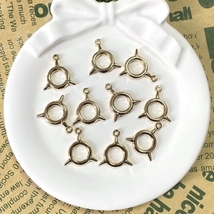 Close-up of 10 pieces gold geometric spiked ring pendants for DIY jewelry in a white tray