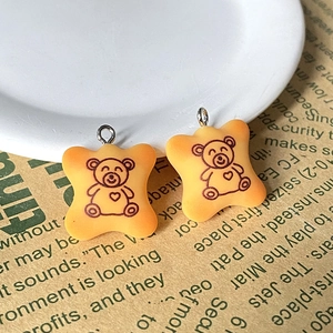 Détails de breloques biscuits ours en résine jaune avec anneau argenté sur journal