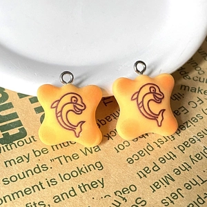 Gros plan de breloques en résine orange avec motif dauphin et boucles métalliques DIY