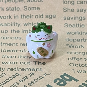 Dettaglio del ciondolo Maneki Neko in lega con fiori di ciliegio e moneta d'oro