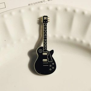 Primer plano detallado de un colgante de guitarra de rock en acrílico con diseño negro y oro