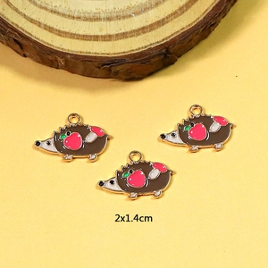 Detailed close-up of a 2x1.4cm hedgehog charm pendant with brown enamel and red apple icon