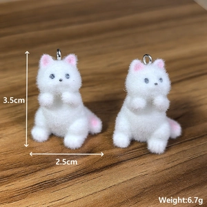 Close-up of 3.5cm white flocked resin cat pendants with pink ears and metal ring detail