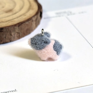 Macro shot of fluffy pink and grey flocked pig pendant with silver metal ring connector