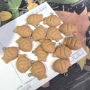Detailweergave van kleine harsvispendants voor DIY-sieraden op een witte kaart