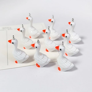 Close-up van schattige witte ganzen hangers van hars met oranje snavels en metalen ring