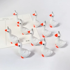 Macro-opname van 10 witte ganzenhangers van hars met oranje snavels en metalen ringen