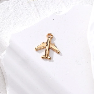 Colgante de avión dorado minimalista para joyería DIY sobre piedra con textura