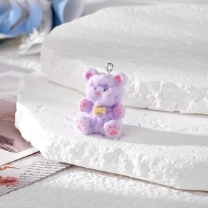 Close-up of purple flocked teddy bear pendant with silver loop and yellow bow detail