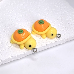 Macro shot of two creative resin turtle pendants featuring orange persimmon shell design