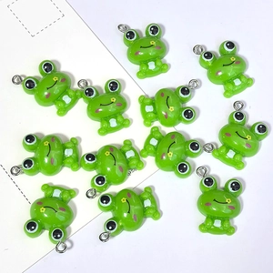 Detalle de lindos dijes de rana de resina con acabado verde brillante y aros metálicos
