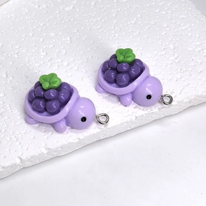 Close-up of resin turtle charms with purple grape shell design and silver metal rings
