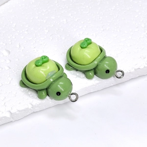 Close-up of green resin apple turtle pendants with silver metal loops for DIY jewelry