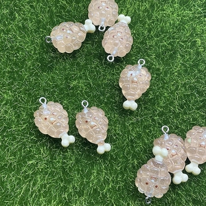 Detailed view of resin chicken leg charms with textured surface on green grass