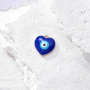 Ciondolo a cuore malocchio blu in lega dorata su una superficie di pietra bianca