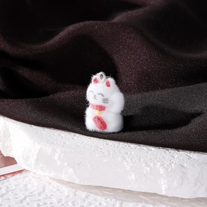 Close-up of a white flocked lucky cat pendant with red ears and a yellow bell detail