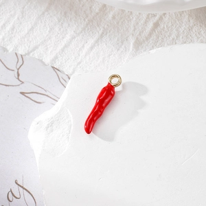 Vista macro di ciondolo a peperoncino in smalto rosso lucido con anello dorato su pietra