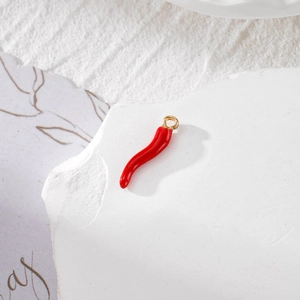 Vista macro di ciondoli a peperoncino rosso con anelli dorati per gioielli fai-da-te