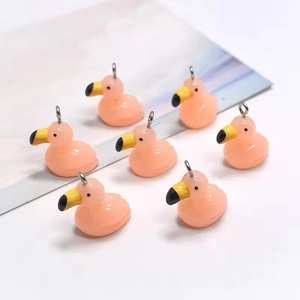 Close-up of resin pink flamingo charms with metal hooks for DIY jewelry making