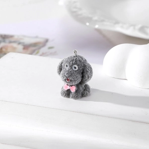 Dettaglio del ciondolo a forma di cane teddy floccato grigio con fiocco rosa e anello