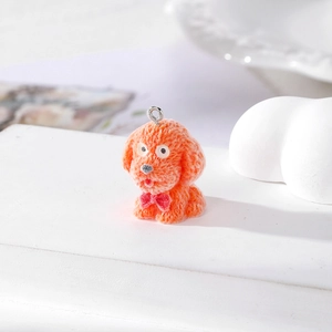 Dettaglio macro del ciondolo a forma di cucciolo floccato arancione con fiocco rosso