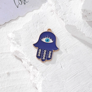 Dettaglio macro del ciondolo mano di fatima con smalto blu e occhio greco su pietra