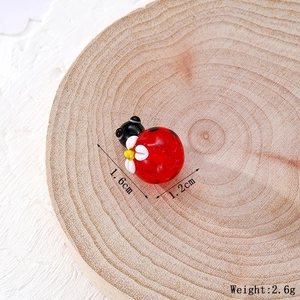 Dettaglio di coccinella in vetro da 1,6cm con margherita bianca su disco di legno