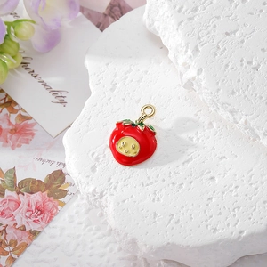 Macro detail of red strawberry charm accessory with green leaf on textured stone