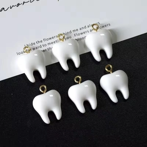 Macro shot of six resin tooth pendants with gold hooks on a premium contrast background