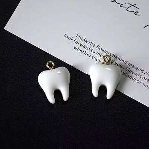 Detail shot of 3D resin tooth pendants with smooth white finish and gold metal loops