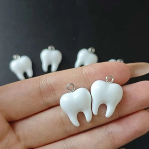Macro detail of resin tooth-shaped charms with silver metal rings for DIY jewelry making
