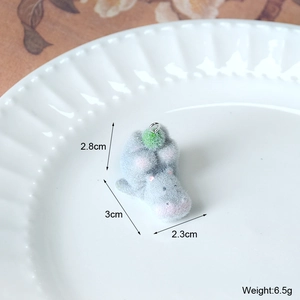 Vue macro du pendentif hippopotame floqué gris avec pompon vert et anneau en métal