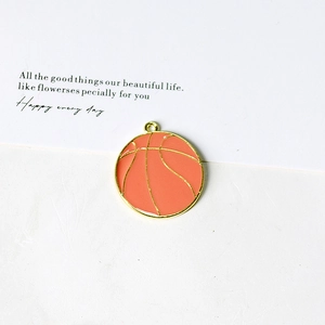 Macro view of a basketball pendant featuring orange enamel and gold-plated details