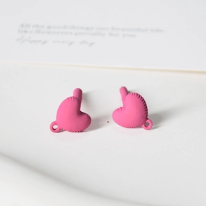 Close-up of matte pink heart-shaped DIY charms with textured edges and hooks