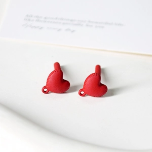 Macro shot of matte red heart-shaped earring components with realistic stitched texture