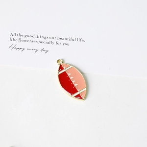 Macro view of red and pink enamel rugby charm pendant with gold plating for jewelry DIY