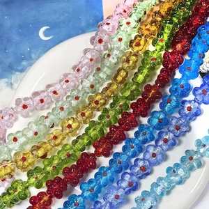 Perles de fleurs en verre coloré sur plat blanc pour création de bijoux DIY