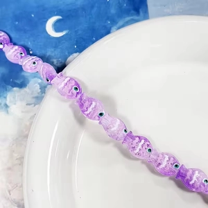 Dettaglio macro di perline di vetro viola a forma di pesce per gioielli fai-da-te