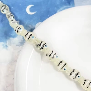 Ciondolo a fantasma con occhio blu su piatto di ceramica bianca con carta luna blu