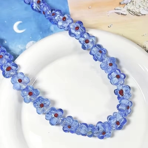 Collier de fleurs en verre bleu sur une assiette blanche avec motif lune en arrière-plan