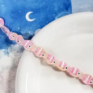 Dettaglio di perle di pesce in vetro rosa traslucido con motivi a onde per gioielli DIY