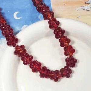 Vue macro de perles en résine rouge translucide en forme de fleur sur plateau blanc