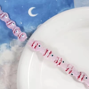 Dettaglio ravvicinato di una perla di vetro rosa a forma di pesce per gioielli