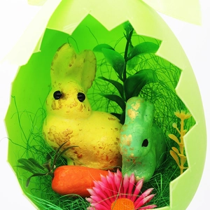 Close-up of Easter bunnies and carrots in decorative foam egg shells with gold glitter