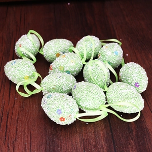 Close-up of Easter foam eggs with floral patterns and green ribbons on wood background