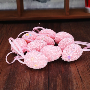 Close-up of pink foam Easter egg ornaments with floral sequins on rustic wood