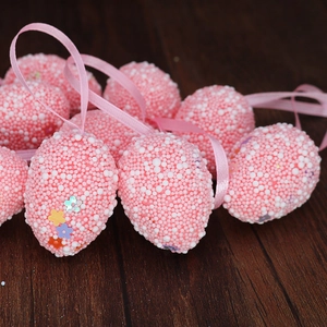 Close-up of pink and white foam Easter eggs with colorful floral sequins and silk ribbons