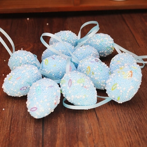 Close-up of light blue speckled Easter eggs with hanging ribbons on wooden background