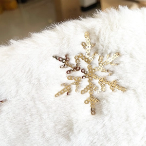Detail of white faux fur Christmas tree skirt with gold sequin snowflake patterns