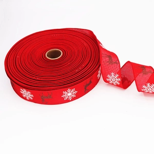 Red Christmas ribbon with gold reindeer and white snowflakes on roll for gift decor